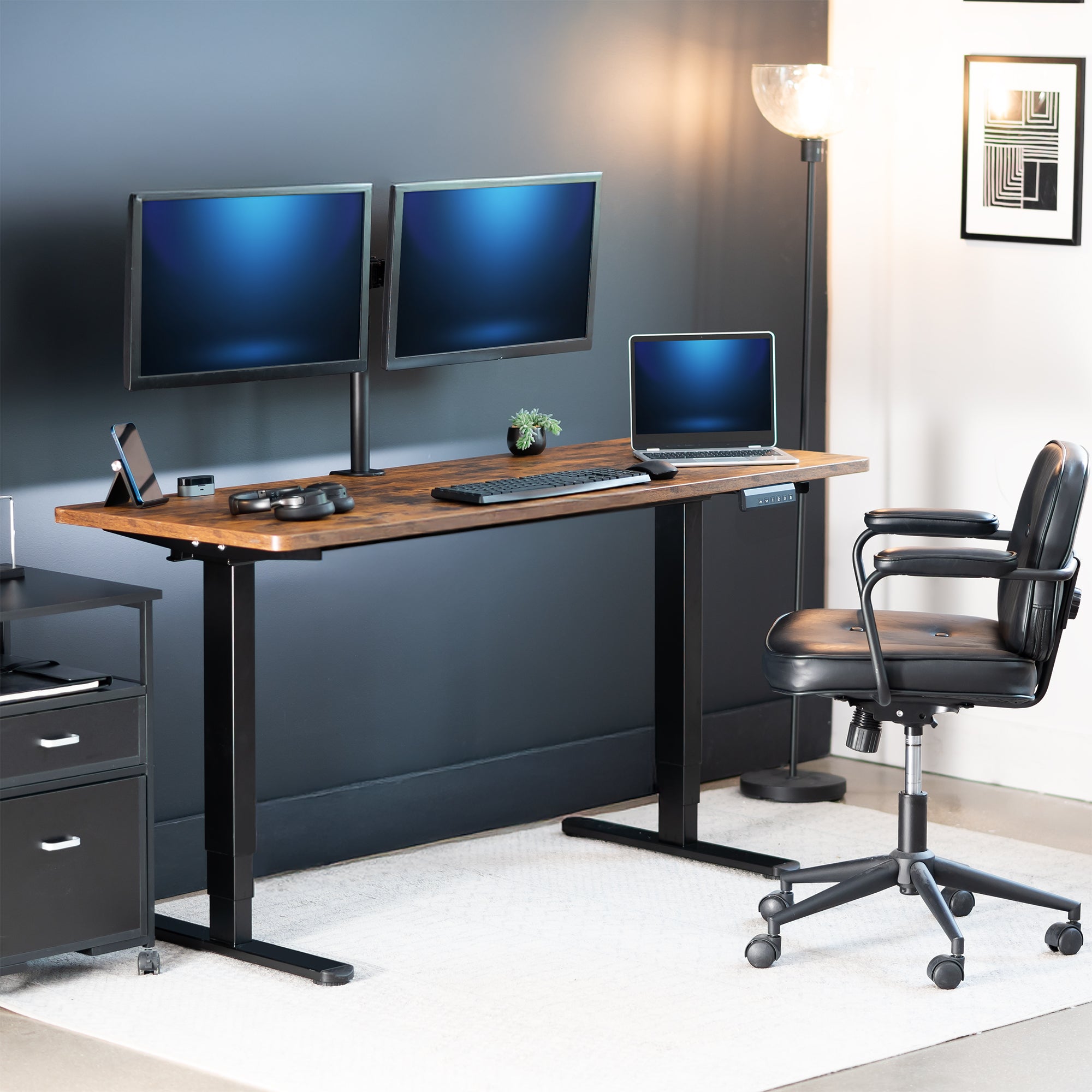 Modern home office setup with a standing desk, computer monitors, and chair.