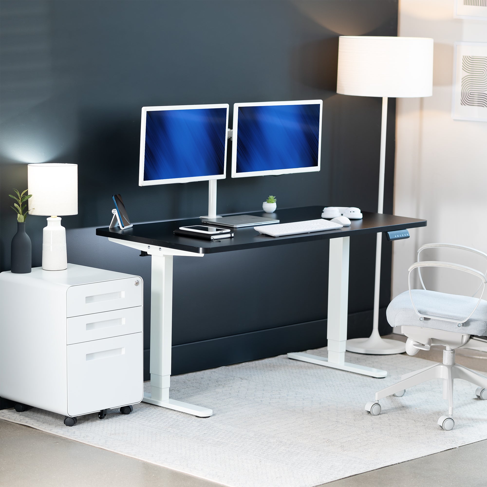 Modern office setup with a black desk, white chair, and two computer monitors.