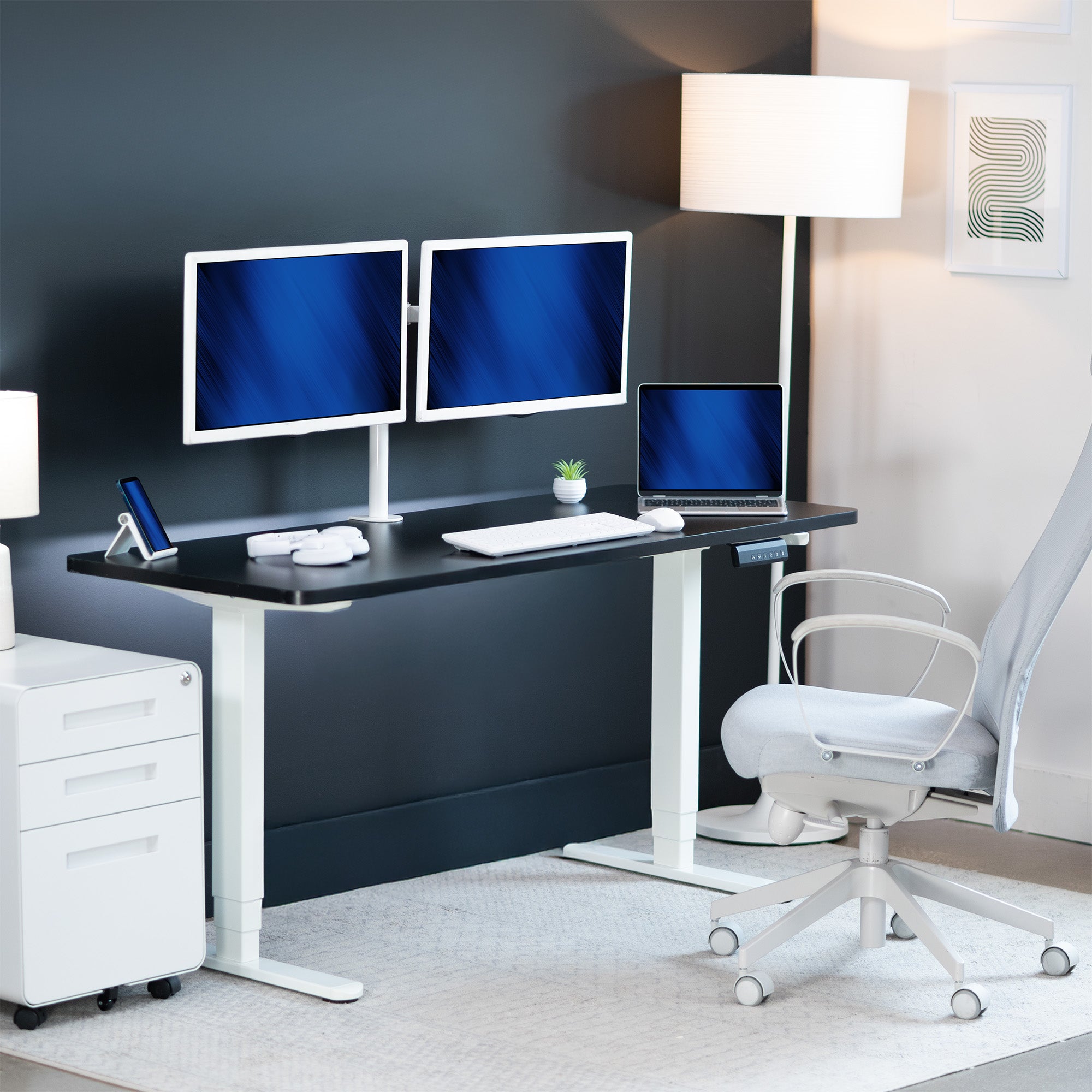 Modern office setup with a standing desk, computer monitors, and chair.
