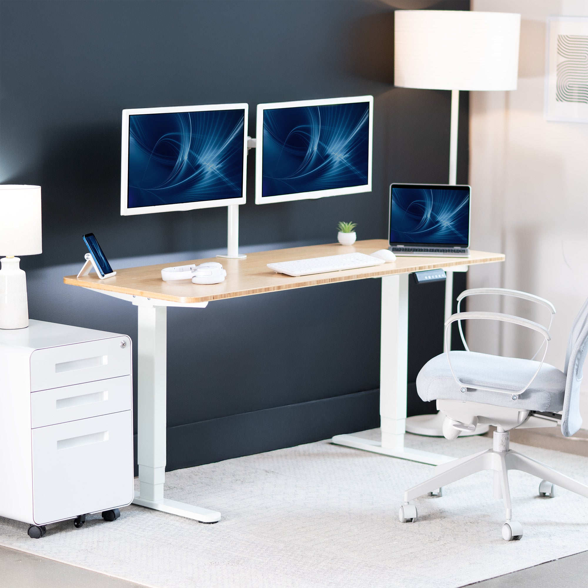 Modern office setup with a standing desk, computer monitors, and a chair.