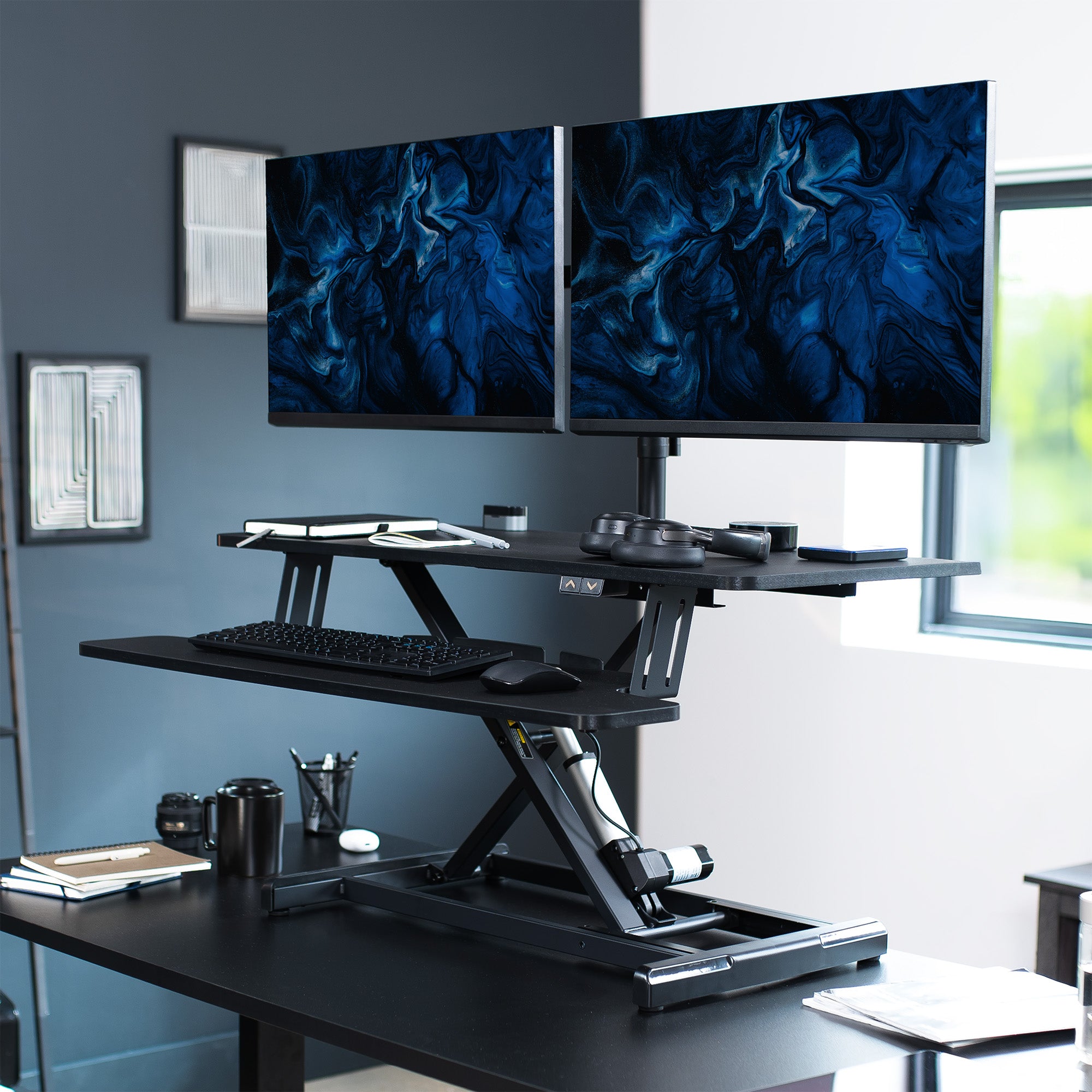 Sit to stand desk riser and dual monitor mount with electric height adjustment.