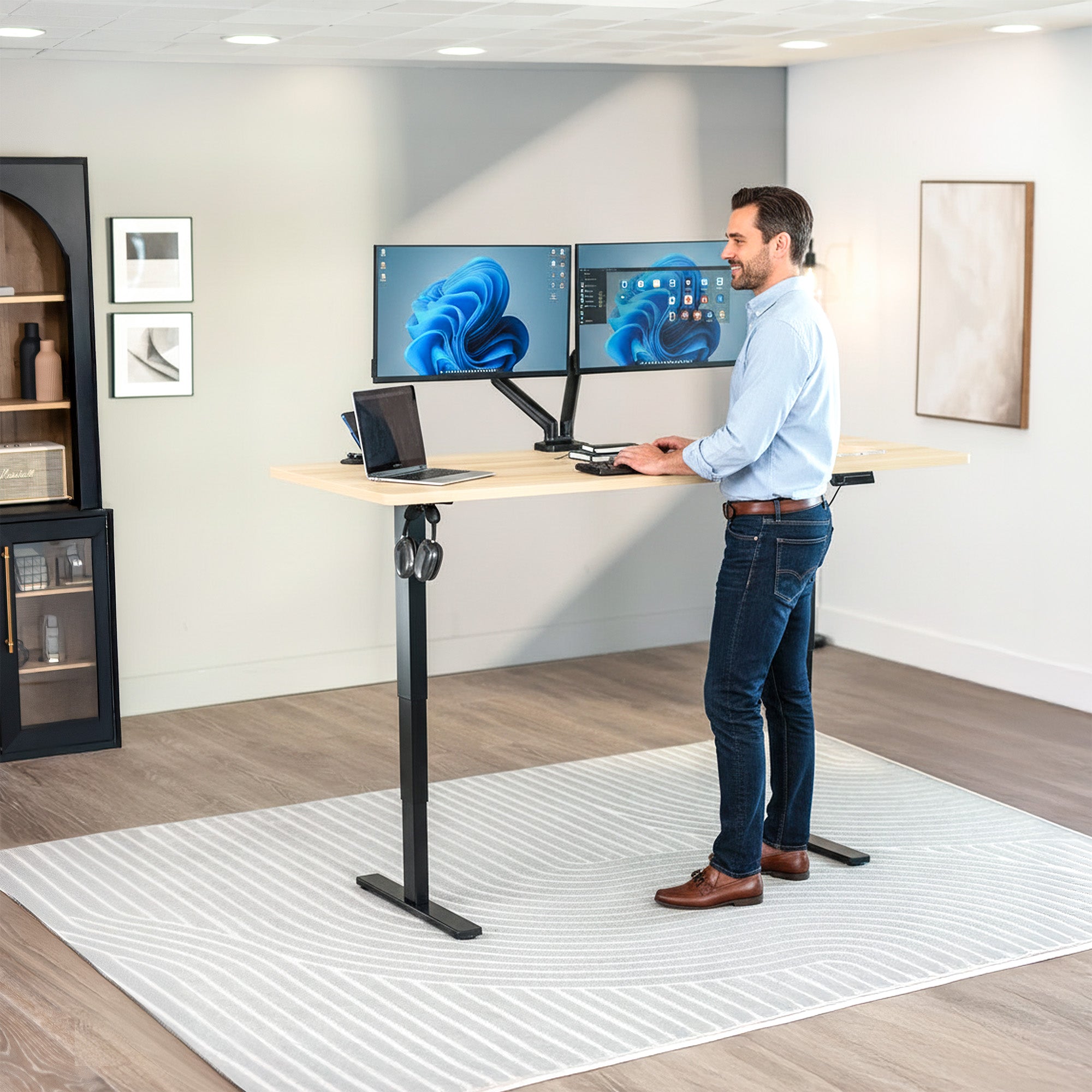 Man using a standing desk with multiple computer monitors in an office setting.