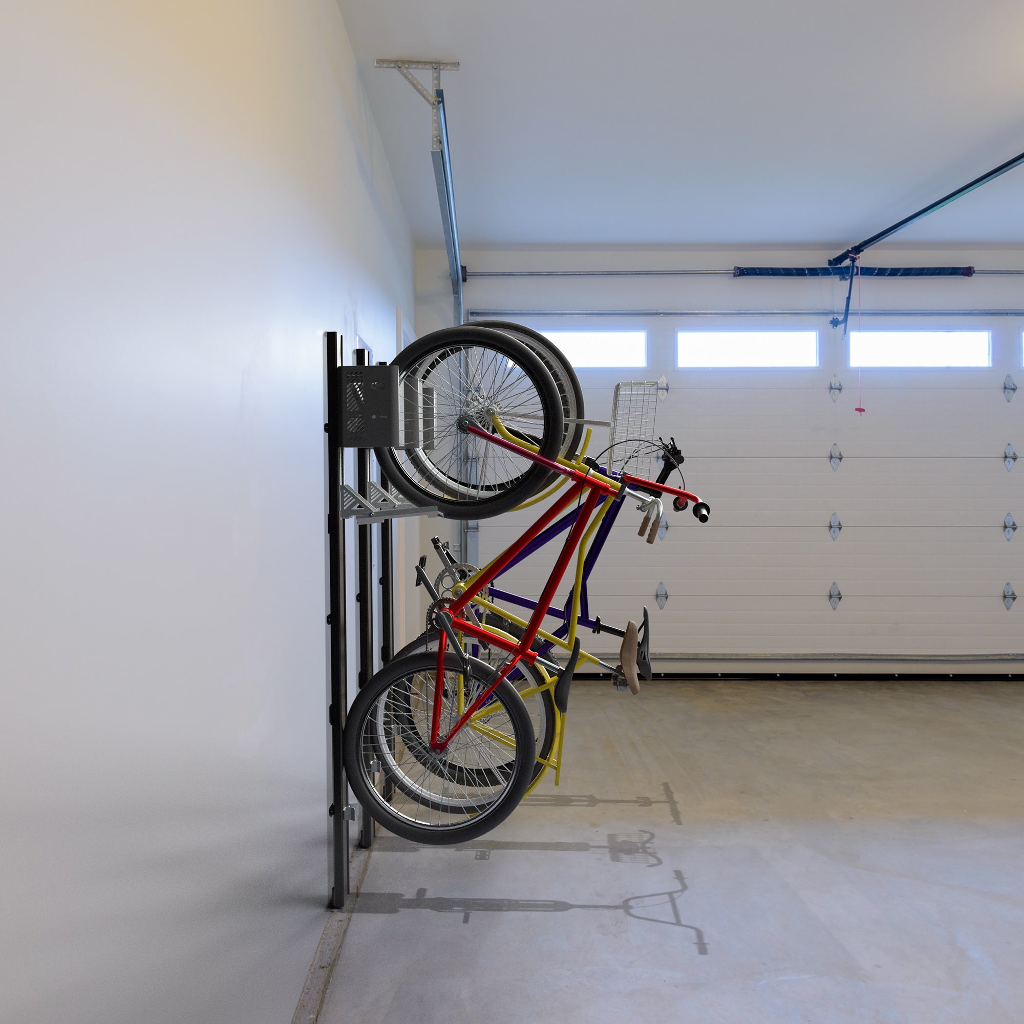 Three bike mounted to the with mechanical lift in an empty garage.