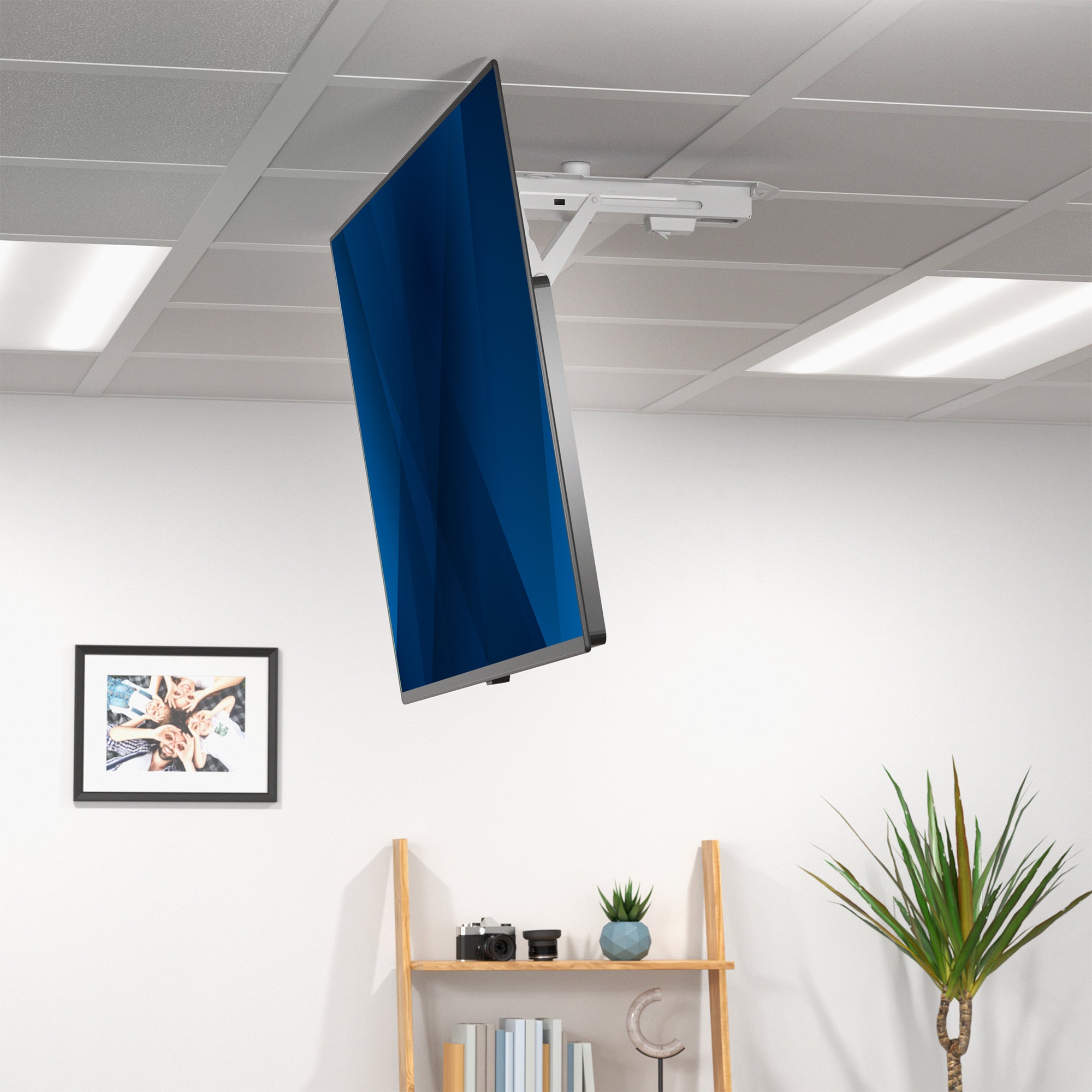 TV mounted on a ceiling with a shelf and plant below.