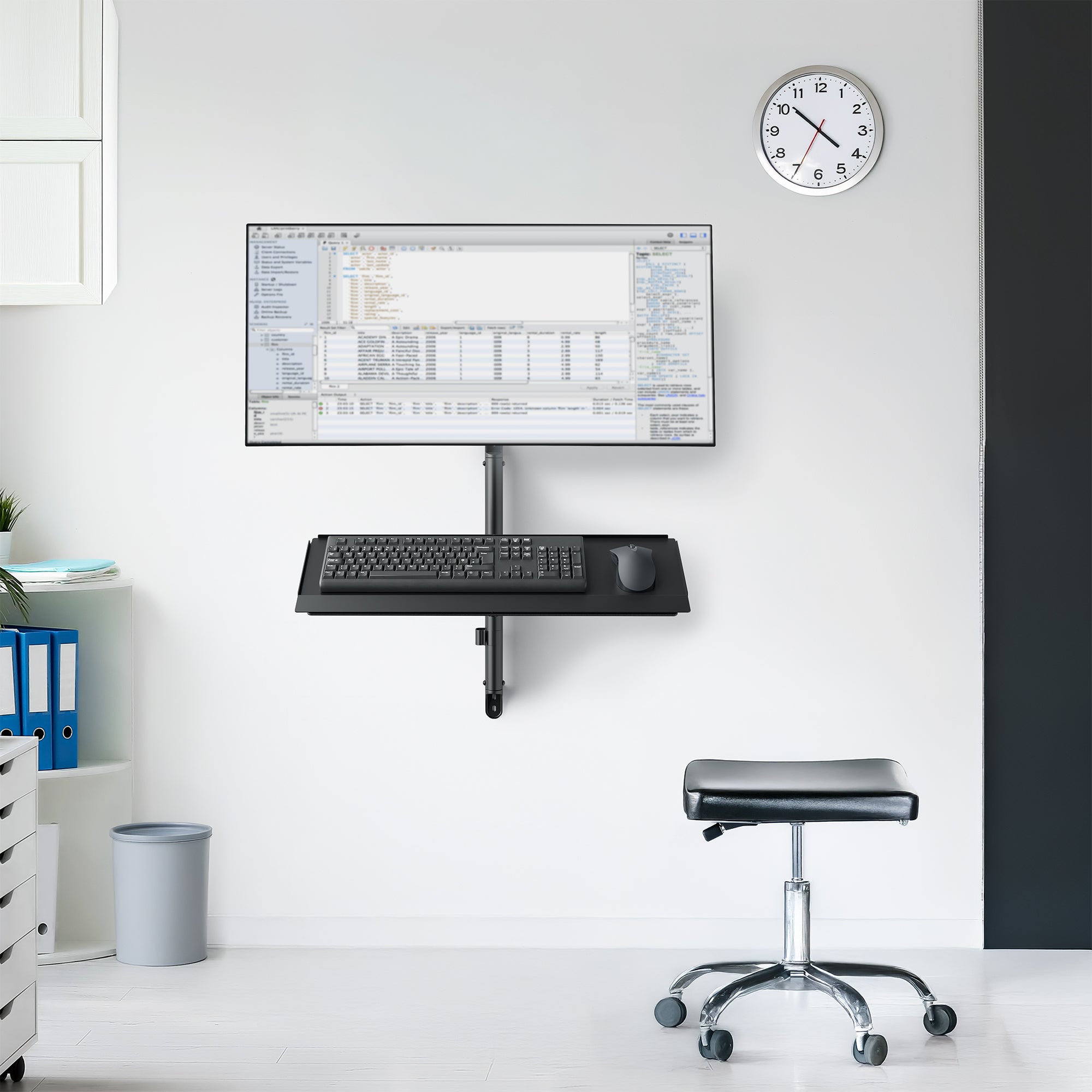 Wall-mounted computer setup with monitor, keyboard, and mouse in an medical space setting.