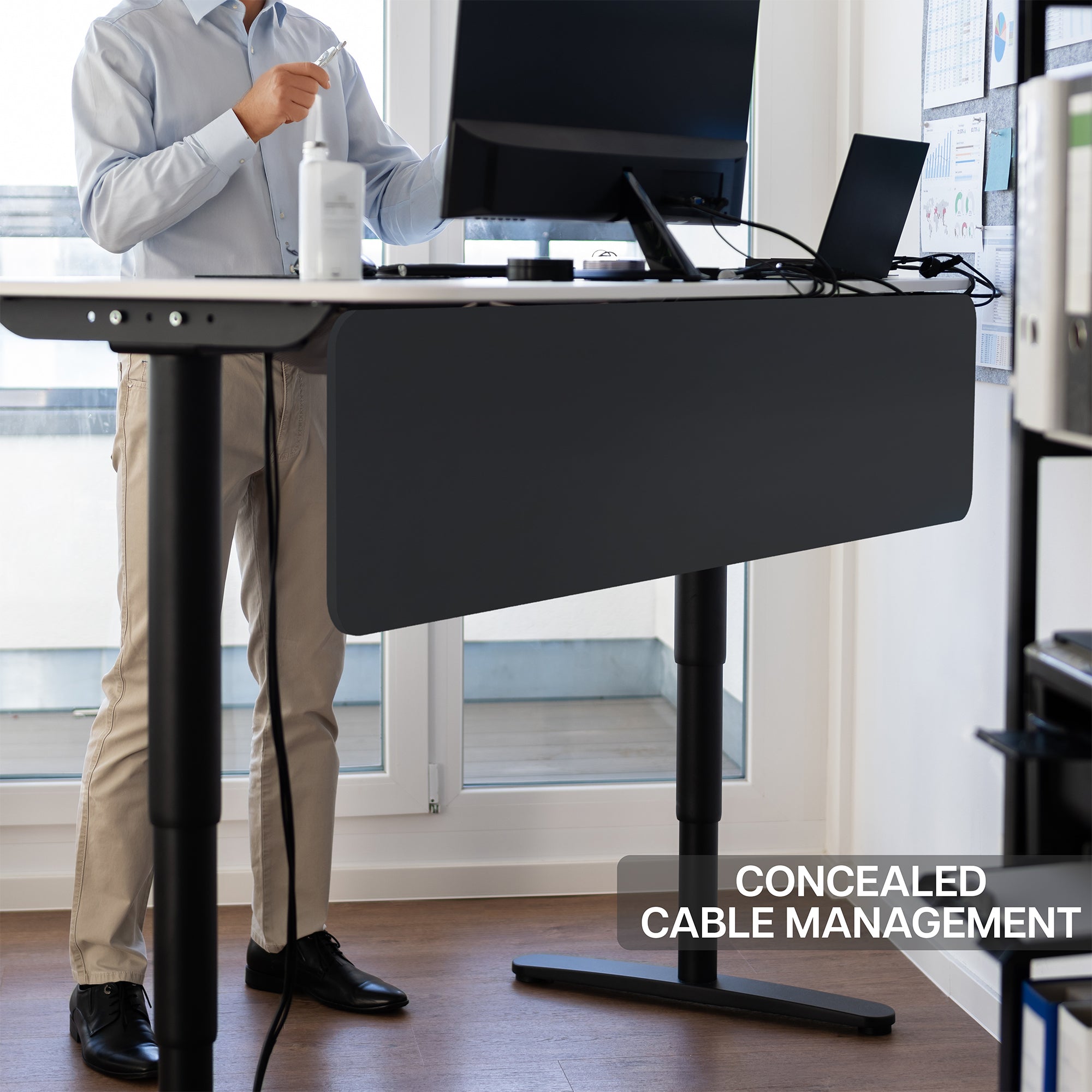 A black laminate modesty panel attached to a desk in an office with concealed cable management.