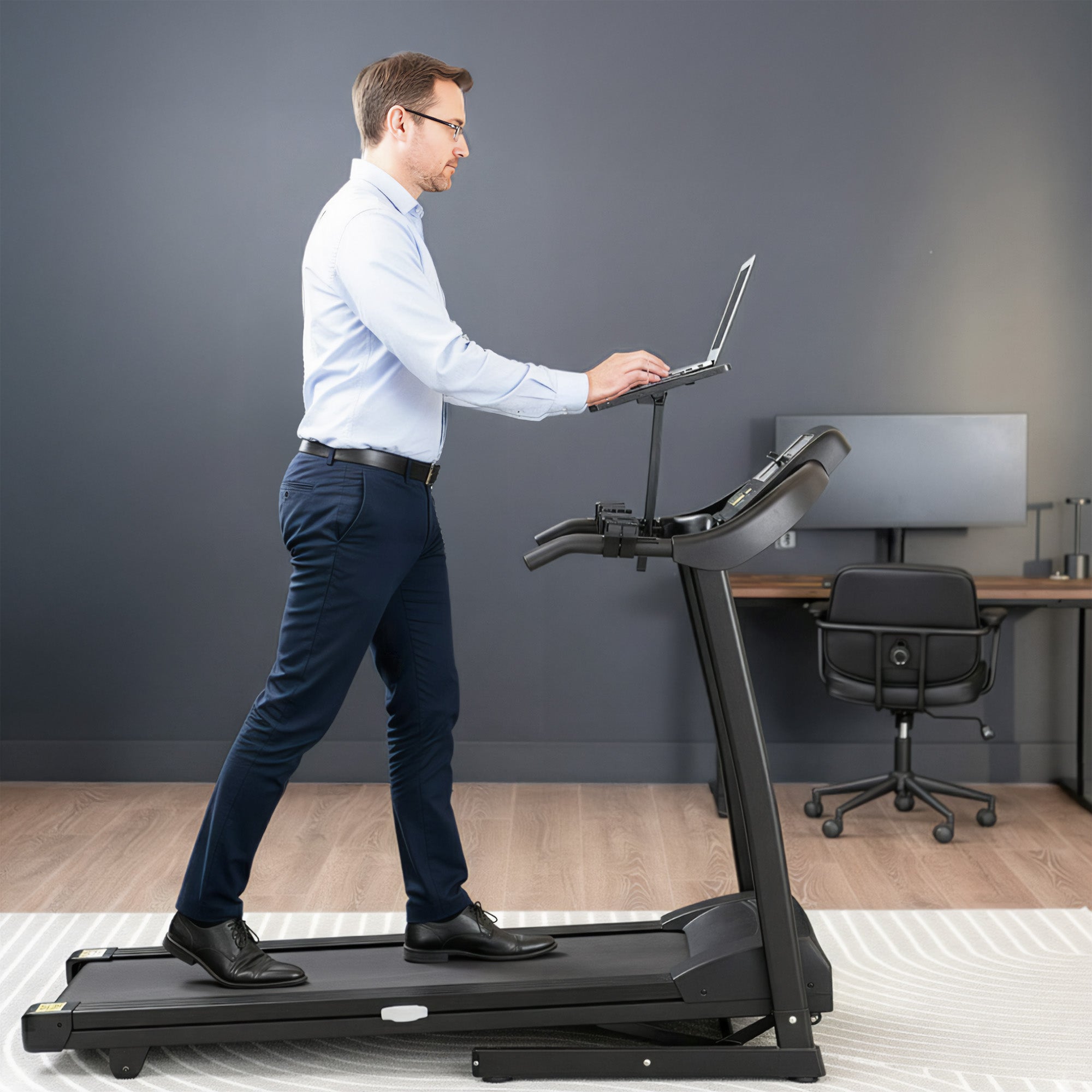 Man using a treadmill desk in an office setting while walking on treadmill.