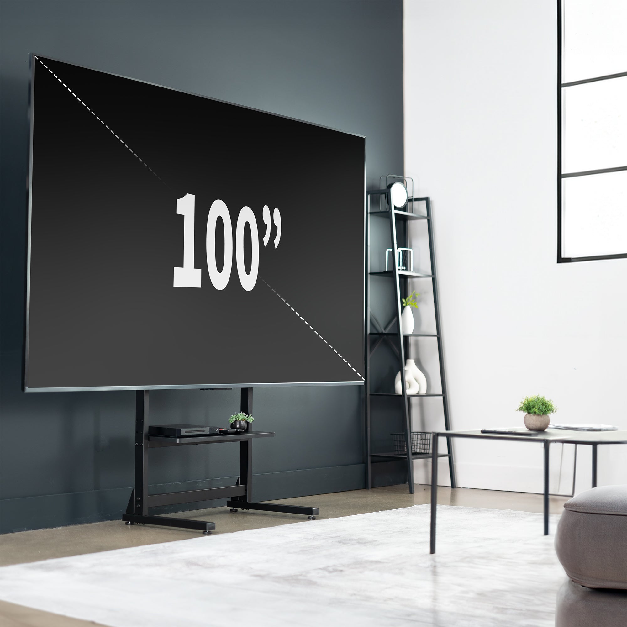 A large flat-screen television mounted on a heavy-duty floor stand set against a gray wall in a modern living room.
