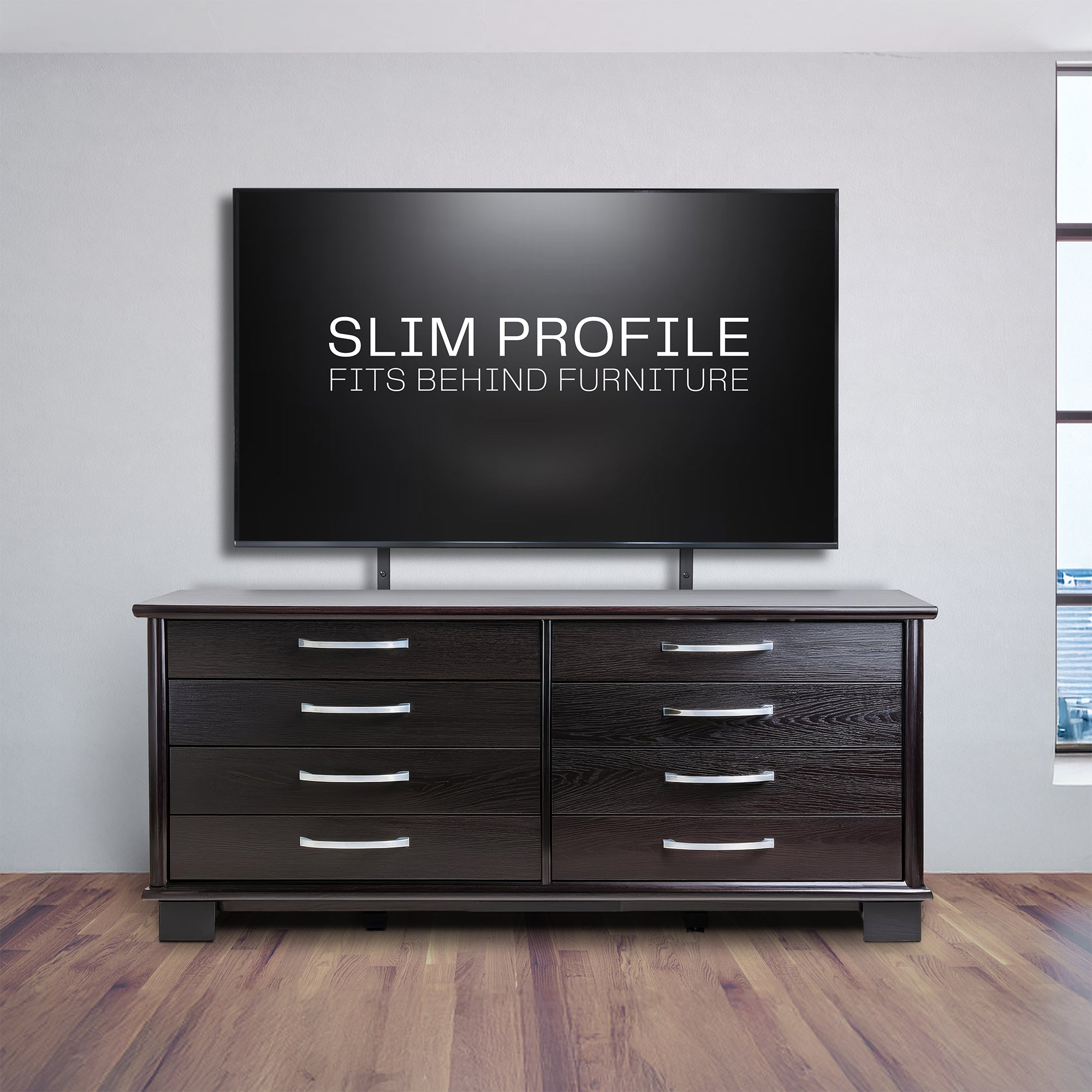 A large flat-screen television on a wooden dresser on a light gray wall.