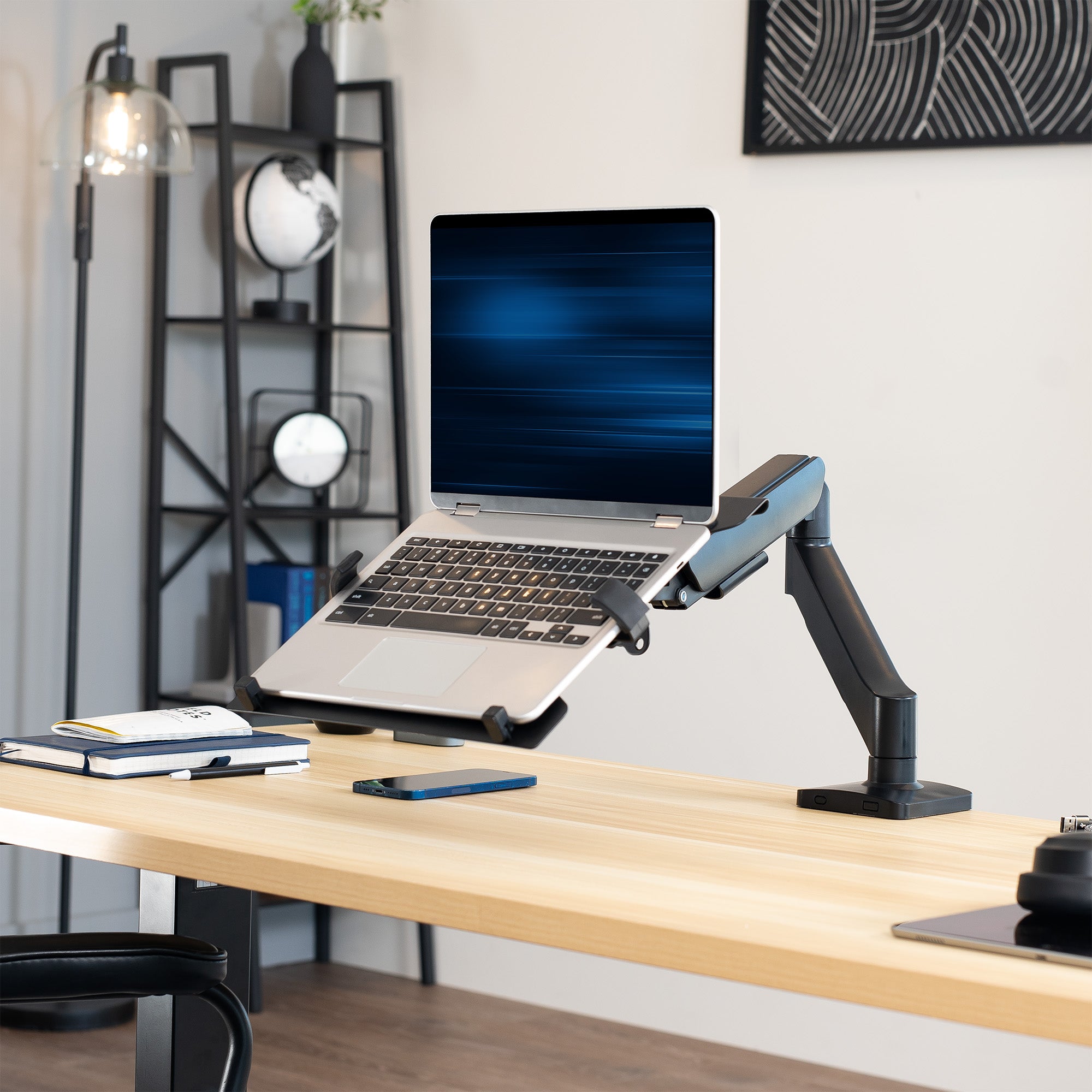 Laptop on a adjustable desk mount on a wooden desk with a modern office background