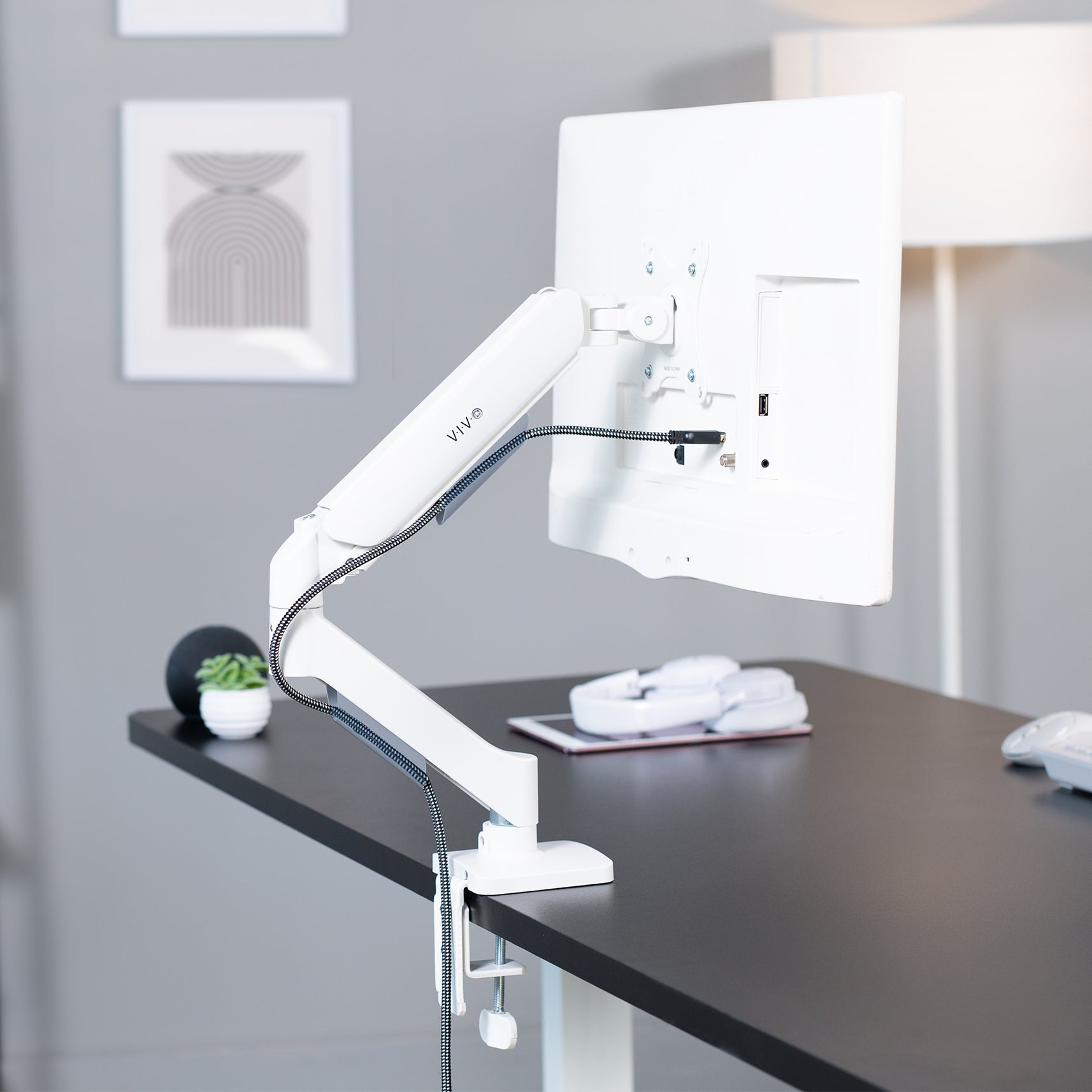 White adjustable monitor stand on a desk with a blurred background