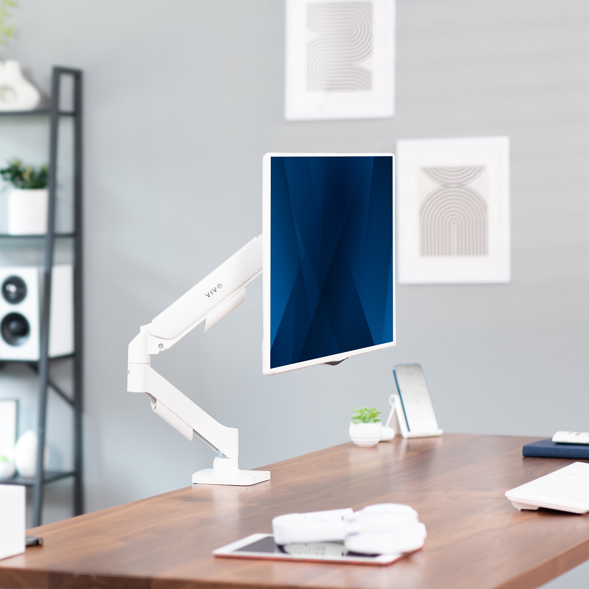 White single monitor mount on desk with desk accessories in an office setup.