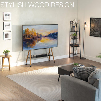 Modern living room with a TV displaying a nature scene on a mobile TV stand and decor items on shelf.
