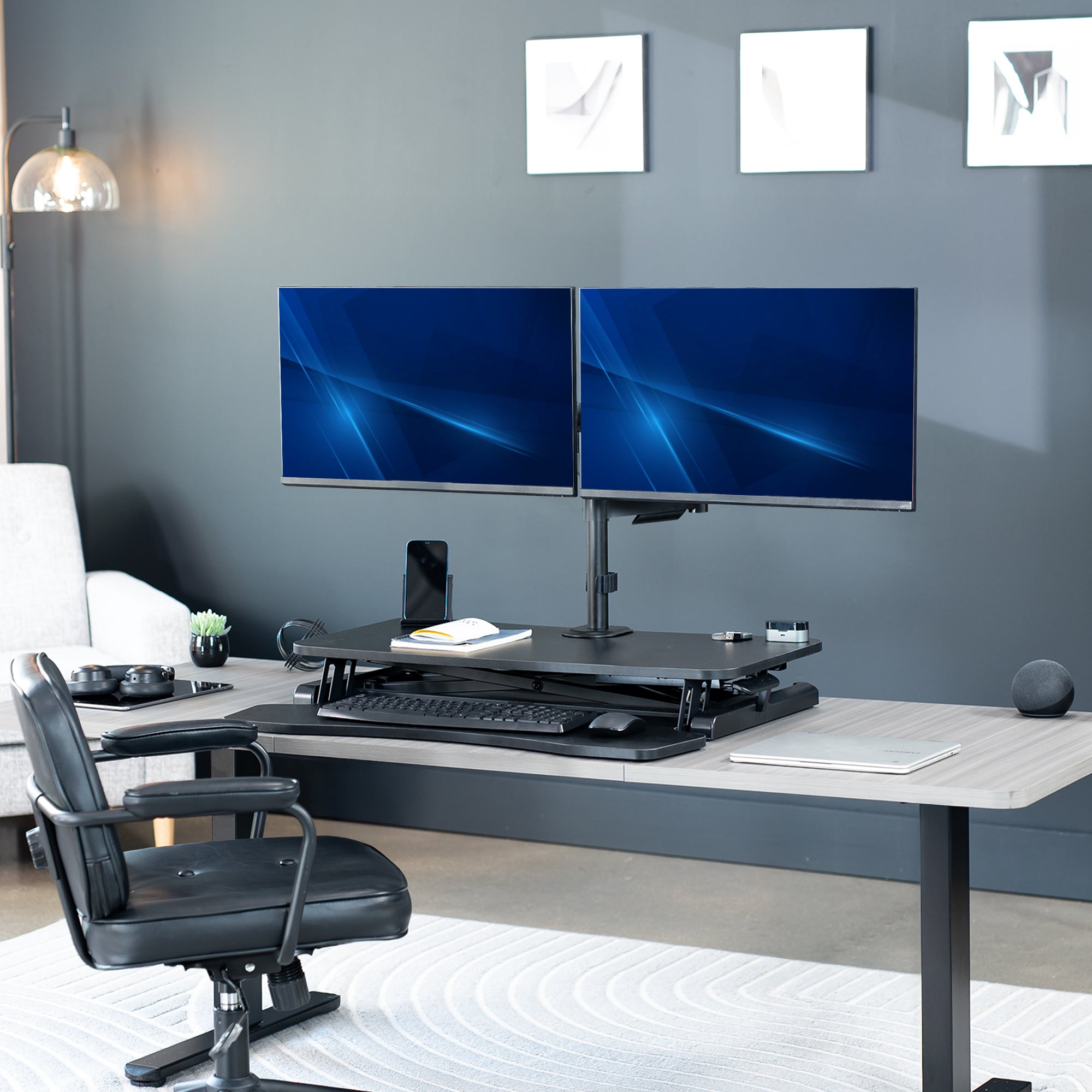 Height adjustable desk riser with articulating mechanical dual monitor mount.