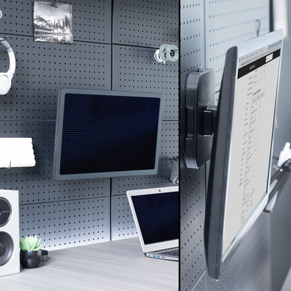 Black metal bracket with a monitor mounted to it on a pegboard wall. 