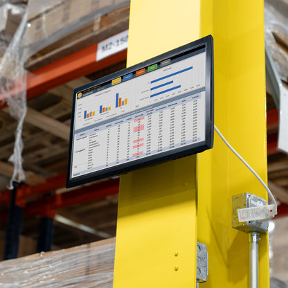 Monitor mounted to a black metal bracket on a yellow pole in a warehouse. 