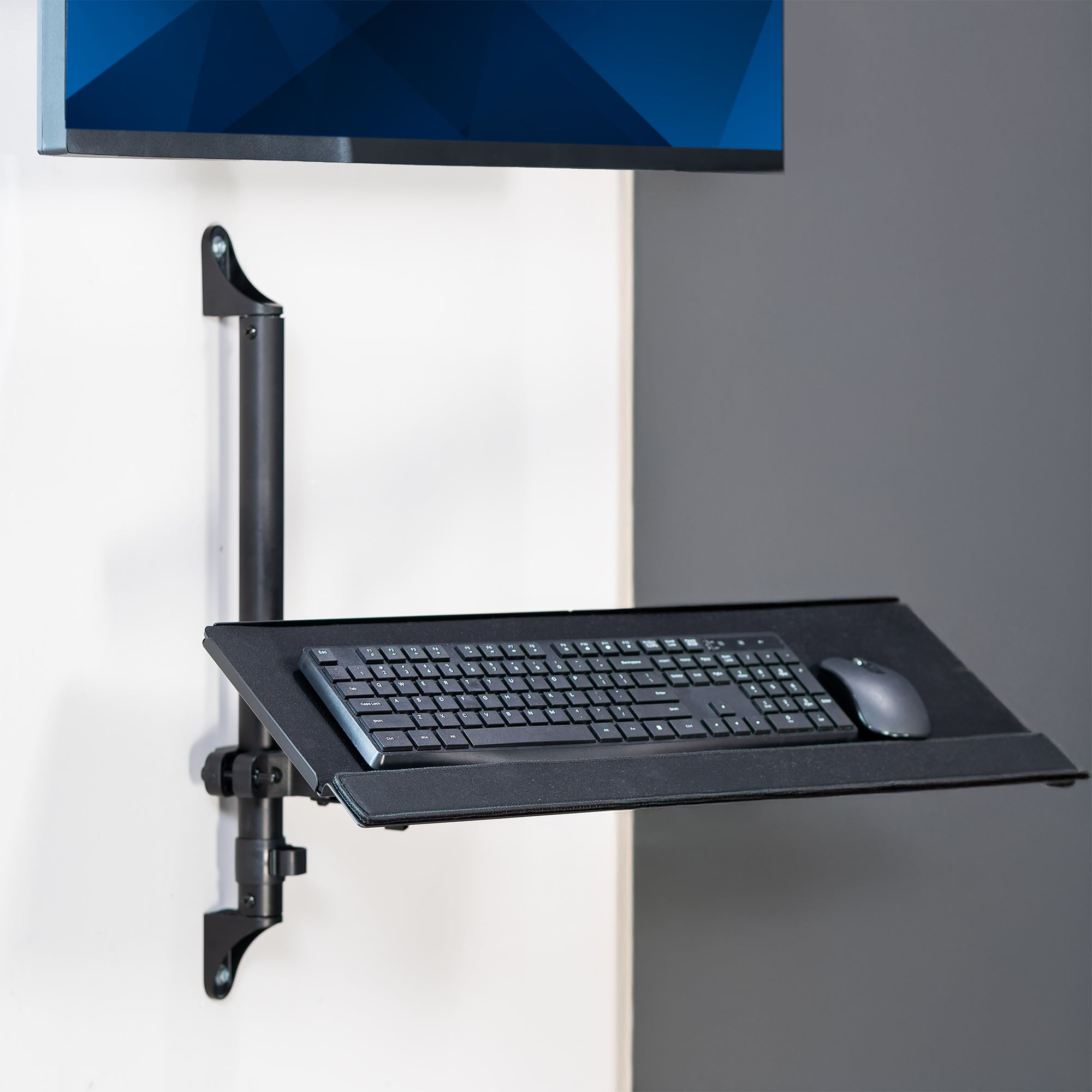 Wall-mounted keyboard tray with a keyboard and mouse on a gray wall.