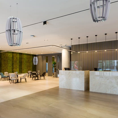 A large oval-shaped acoustic ceiling sound absorber in a light gray color in a minimalist restaurant setting. 