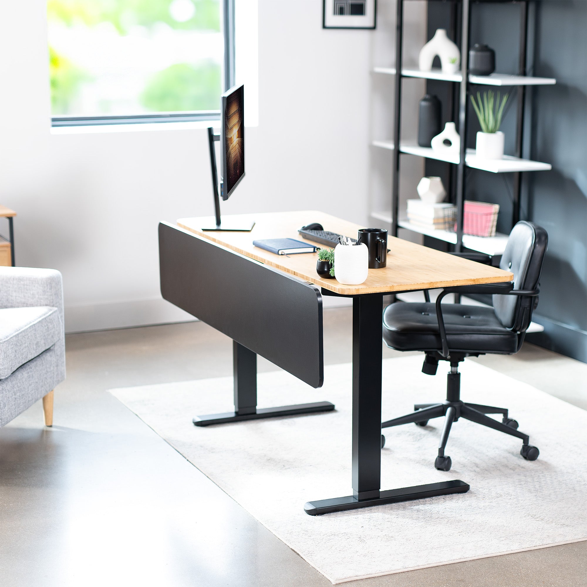 A black laminate modesty panel attached to a wooden desk with a black leg frame in a modern home office.