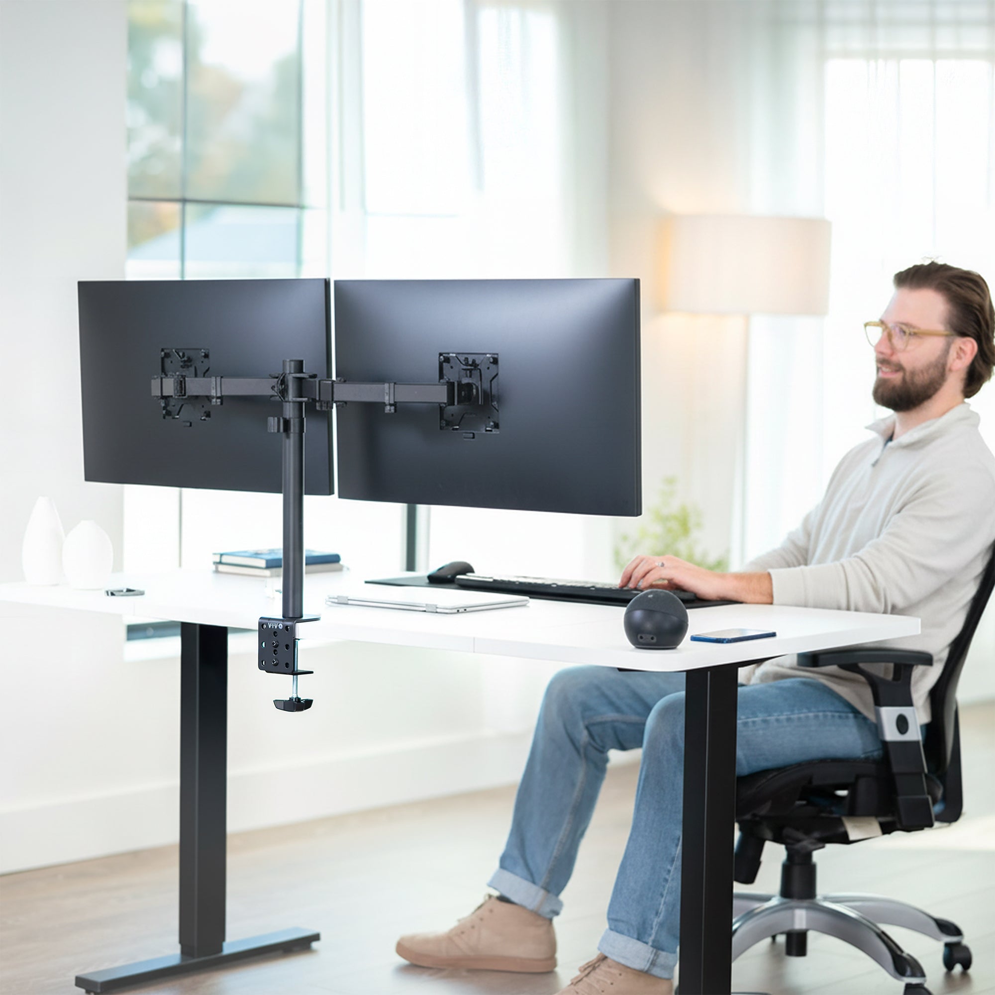 Person using a dual monitor desk mount in home office setting