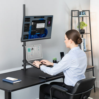 Model sitting at desk with extra tall single monitor mount and laptop tray.