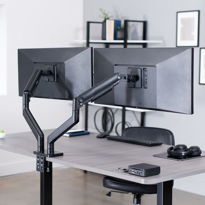 Dual monitor desk mount with pneumatic arms, capable of supporting ultrawide screens on desk in office space.