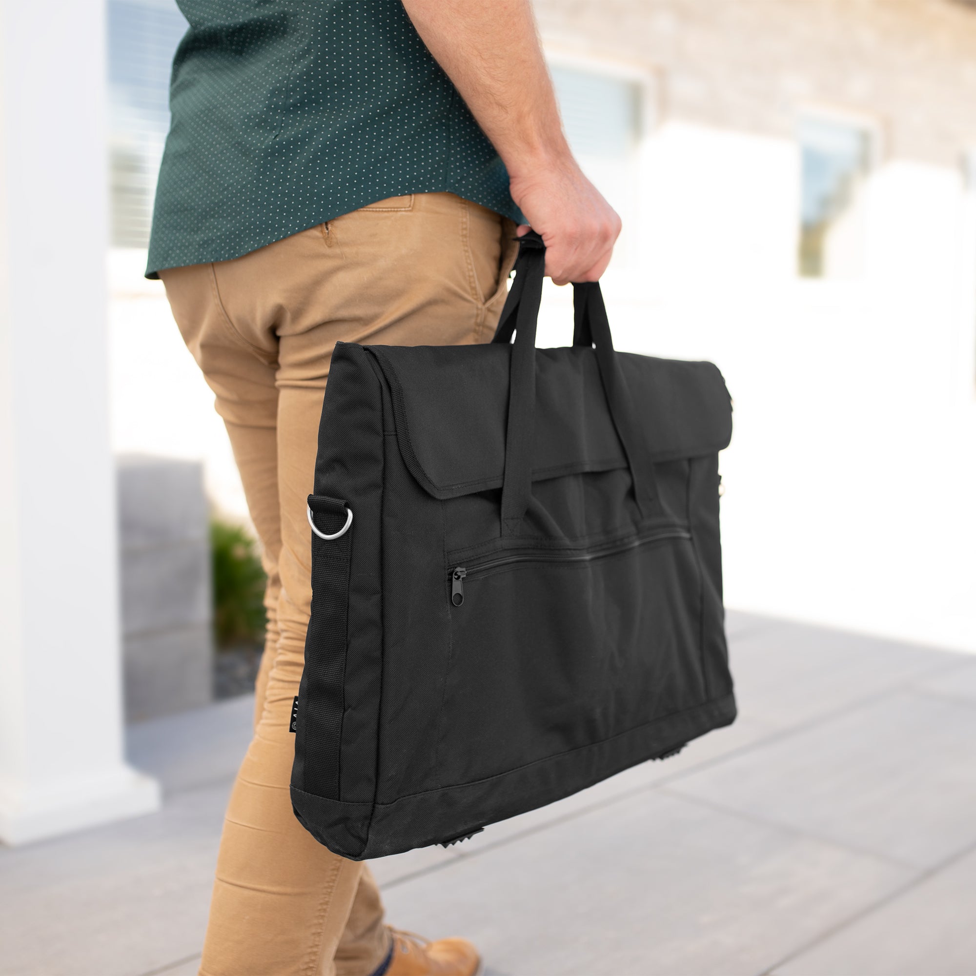 A black monitor travel case with a shoulder strap and multiple compartments.